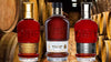 Famille Naud Cognac Combo 750 ML, three bottles with rich amber color, displayed in a rustic cellar.
